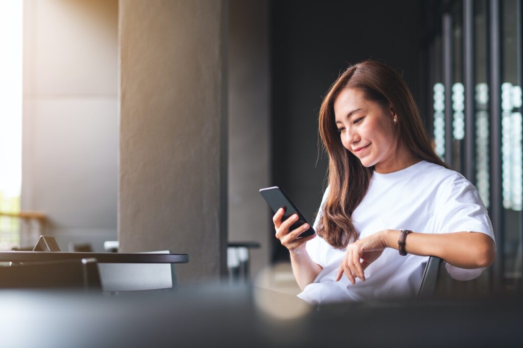 A beautiful young asian woman holding and using mobile phone