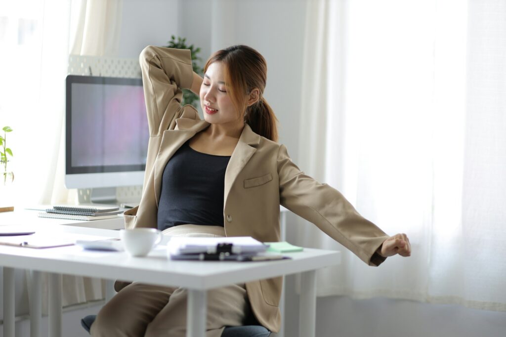 A business woman working in an office stretches to relax from work during breaks.