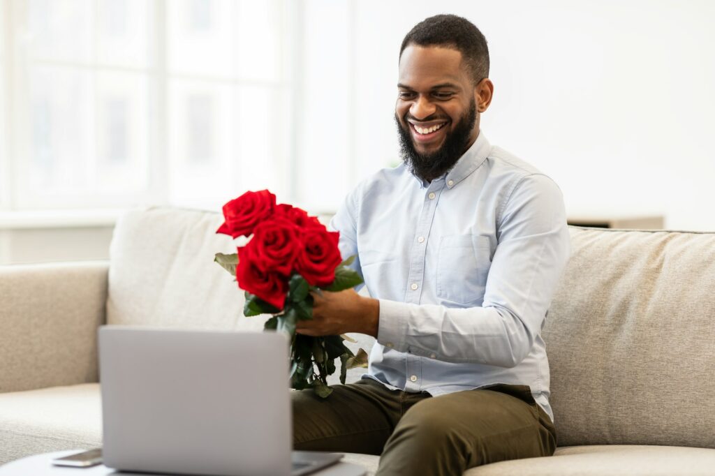 Black man having online date, holding roses, showing to camera