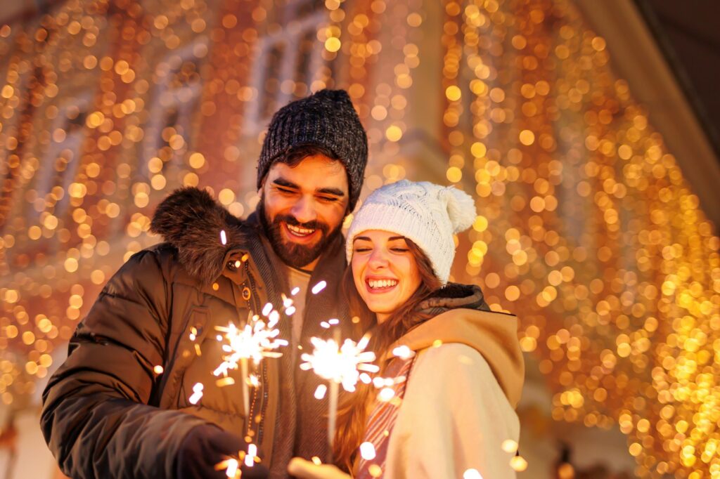 Couple having fun celebrating New Year in the city streets waving with sparklers