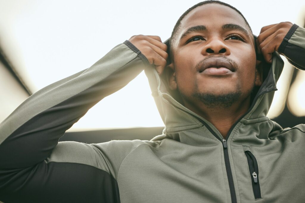 Exercise, mindset and hoodie with a sports black man getting ready for a workout, fitness or runnin