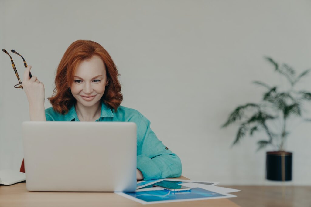 Happy beautiful female financial analyst prepares economic research, works on laptop computer