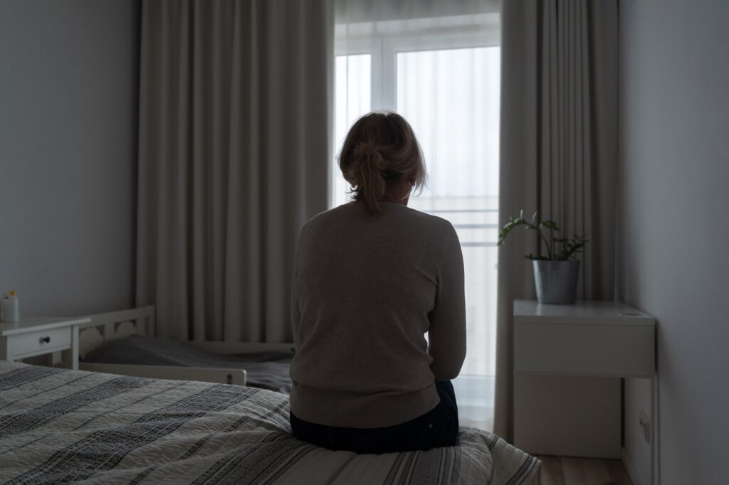 Mature woman sitting alone in the room, sad depressed person. Back view. mental health