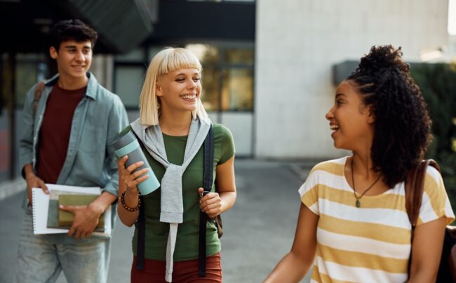 Multiracial group of happy college friends talking at campus.