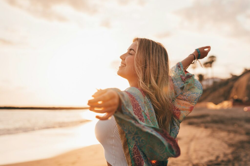 Portrait of one young woman at the beach with openened arms enjoying free time and freedom