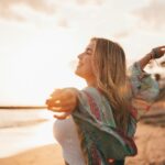 Portrait of one young woman at the beach with openened arms enjoying free time and freedom