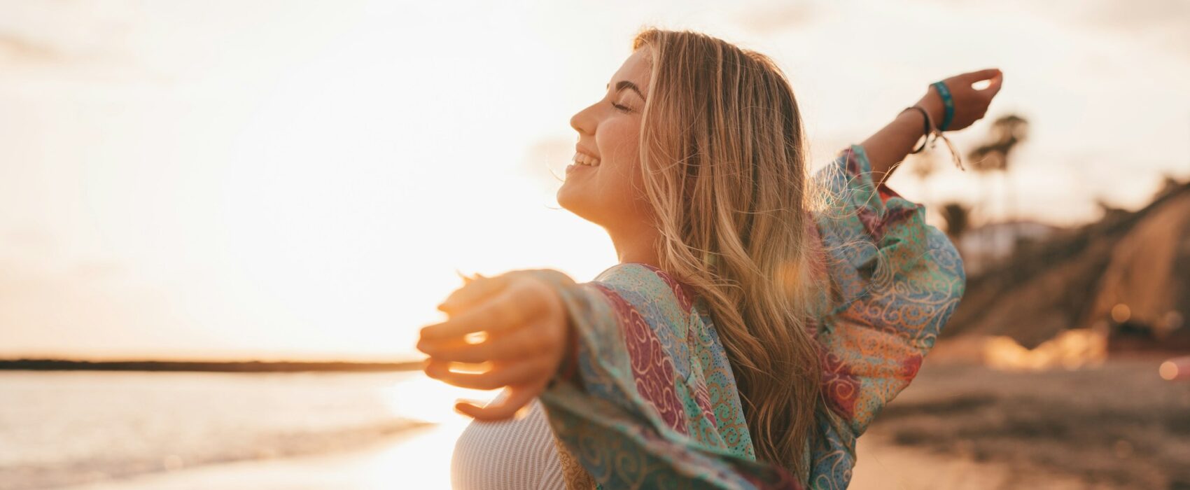 Portrait of one young woman at the beach with openened arms enjoying free time and freedom