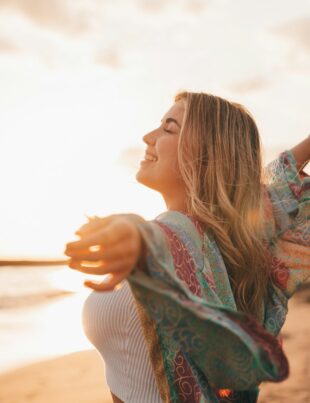 Portrait of one young woman at the beach with openened arms enjoying free time and freedom