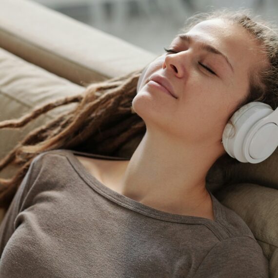 Relaxed girl with headphones smiling while listening to calming music on couch