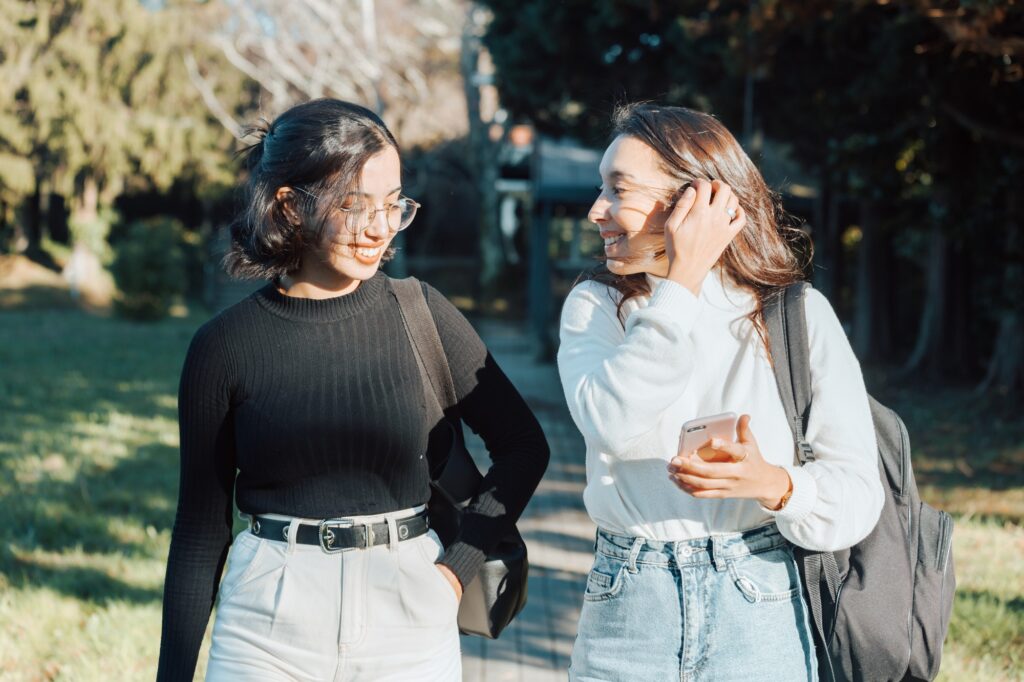 Two young woman students small talking while going to class at the college