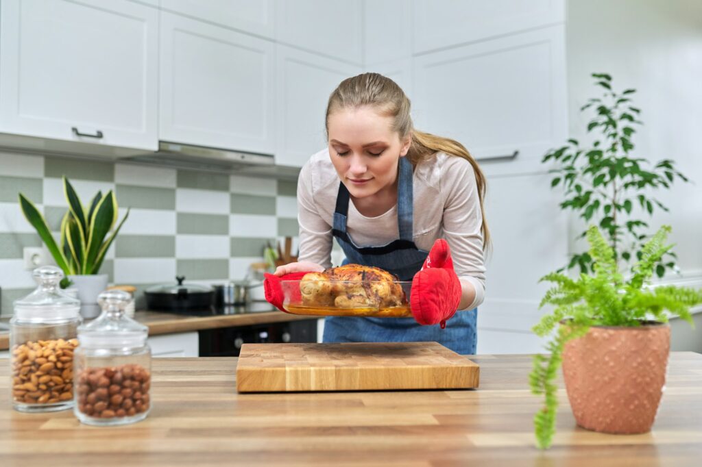 Woman cooking baked chicken at home in the kitchen.