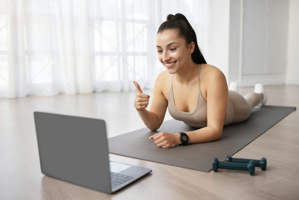 Woman enjoying online fitness class, home interior