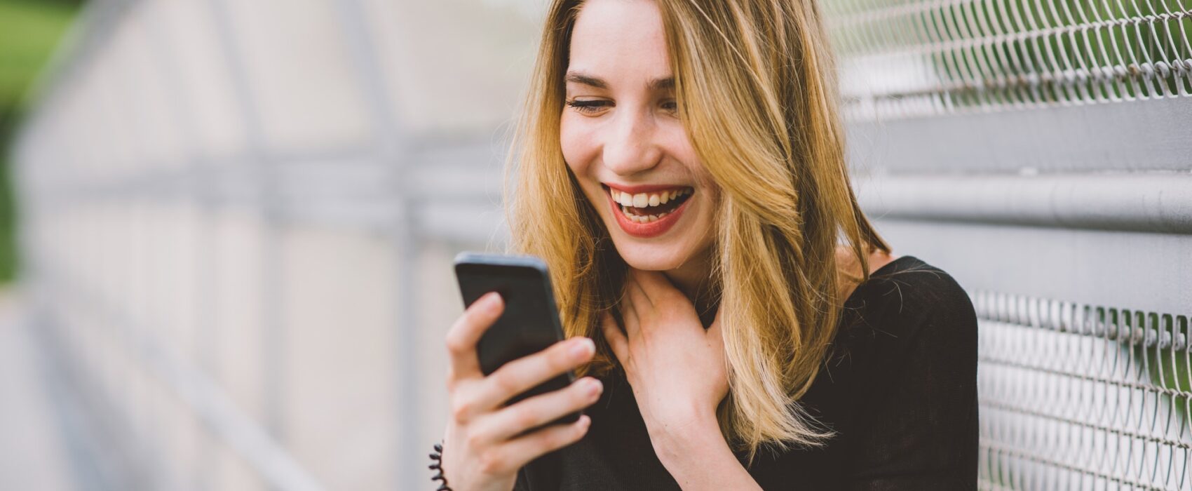 Young woman using smartphone laughing