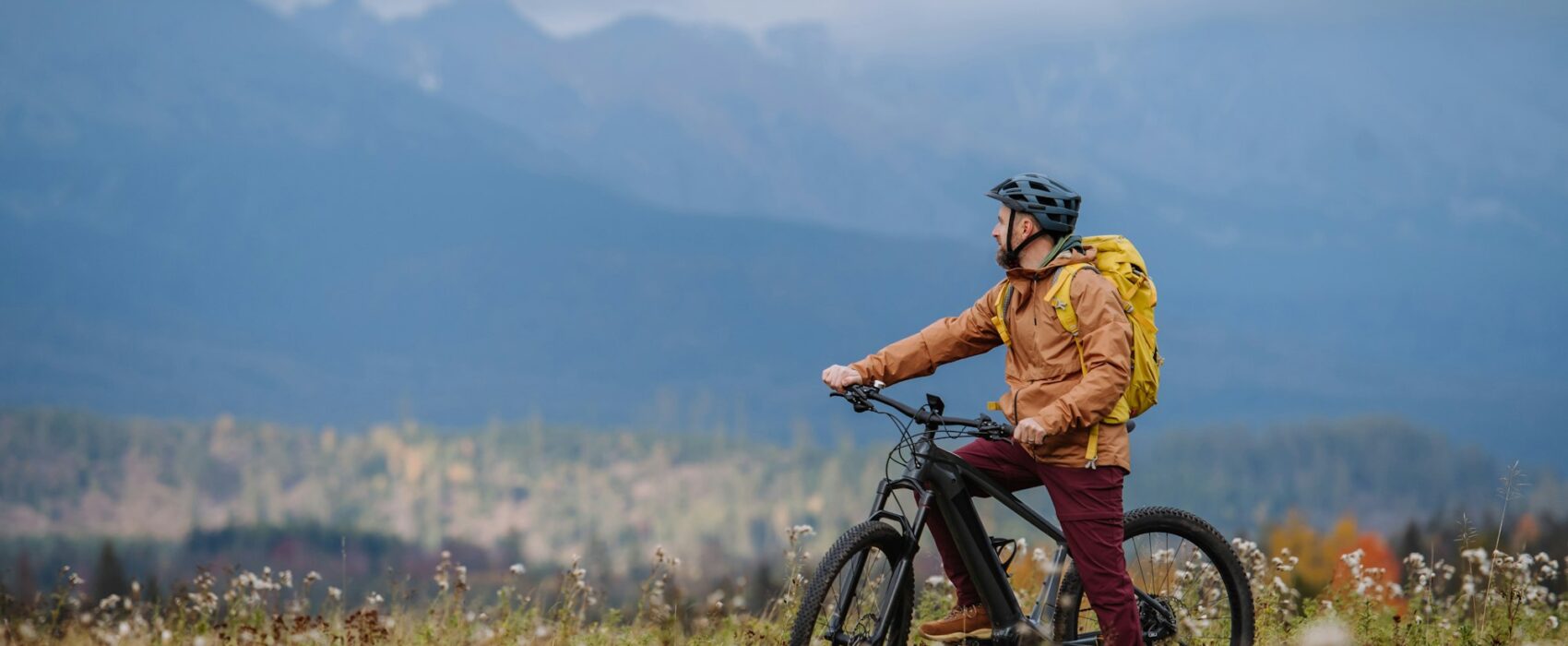 Active man on bike in the middle of autumn nature, admire mountains. Healthy lifestlye concept.