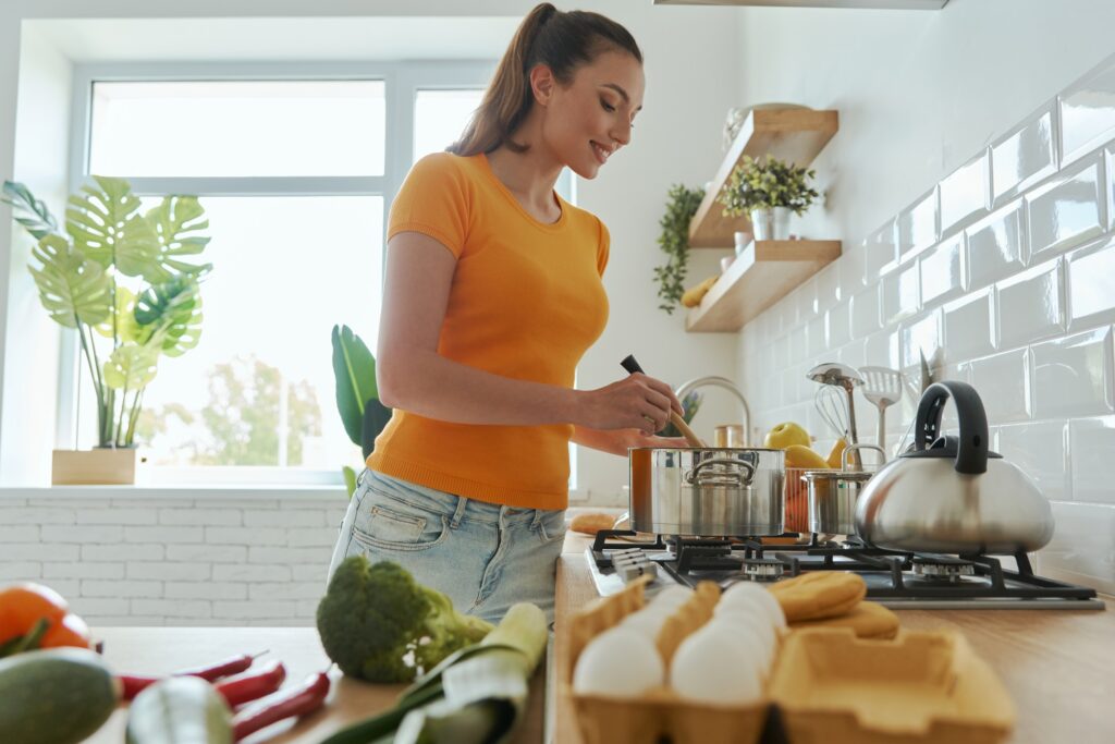 Attractive young woman cooking at the domestic kitchen