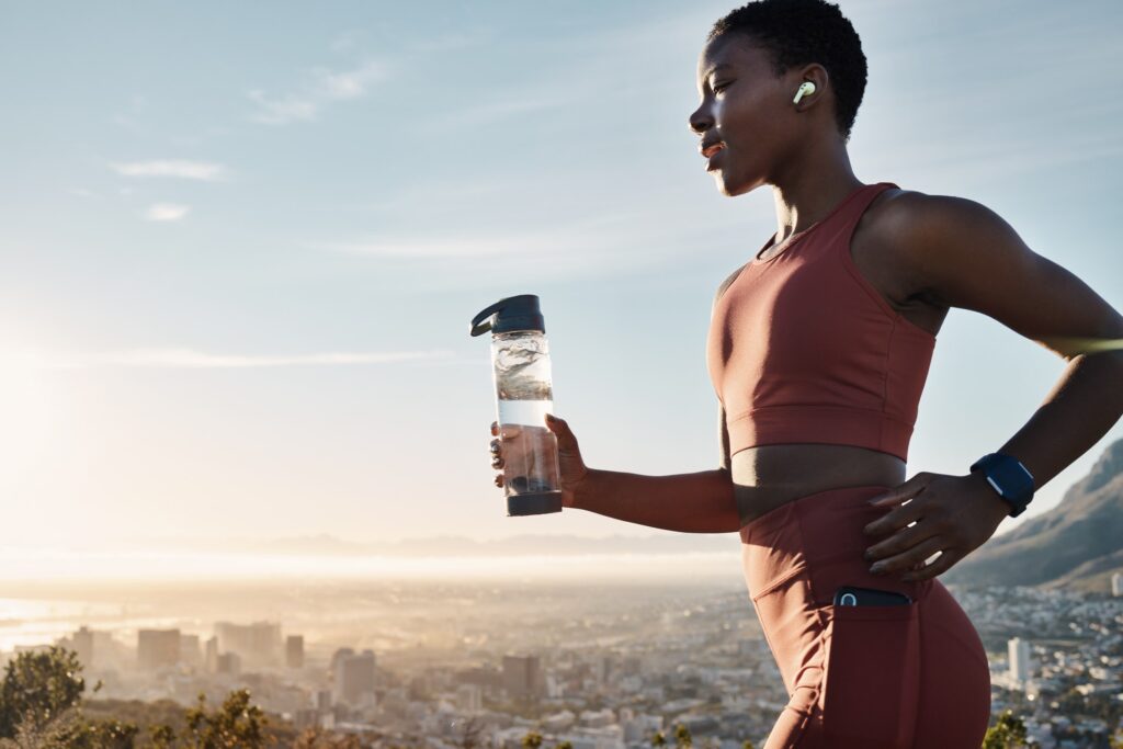 Black woman, water bottle or earphones in running workout goals, healthcare wellness training or su