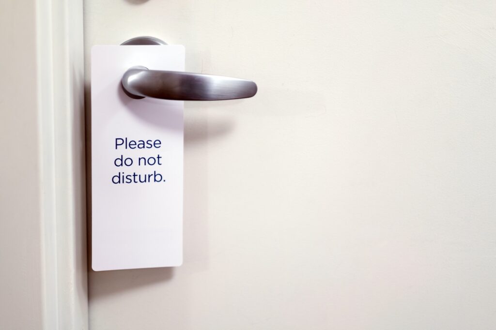 Closed door of hotel room with please do not disturb sign