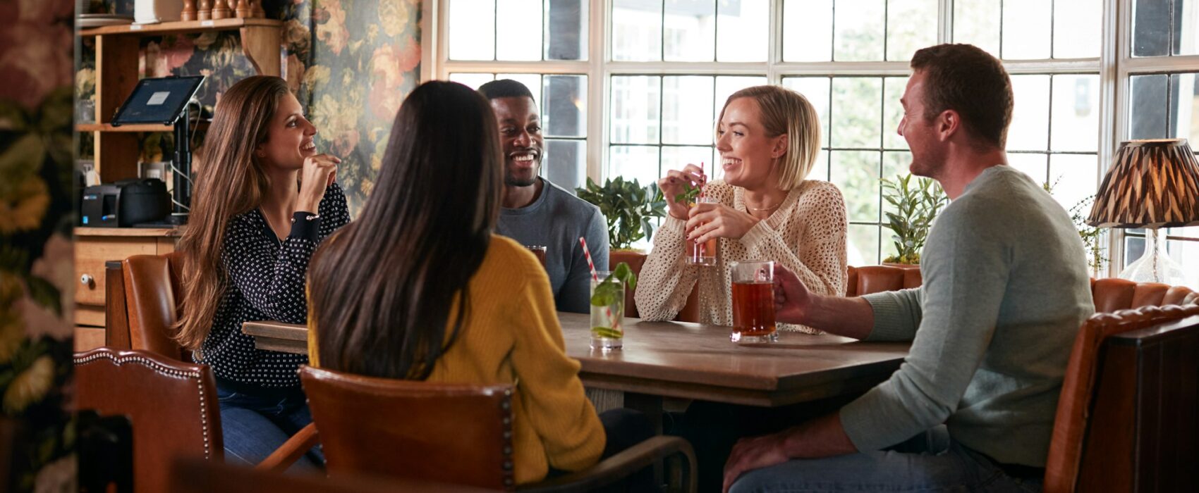 Group Of Friends Meeting For Lunchtime Drinks In Traditional English Pub