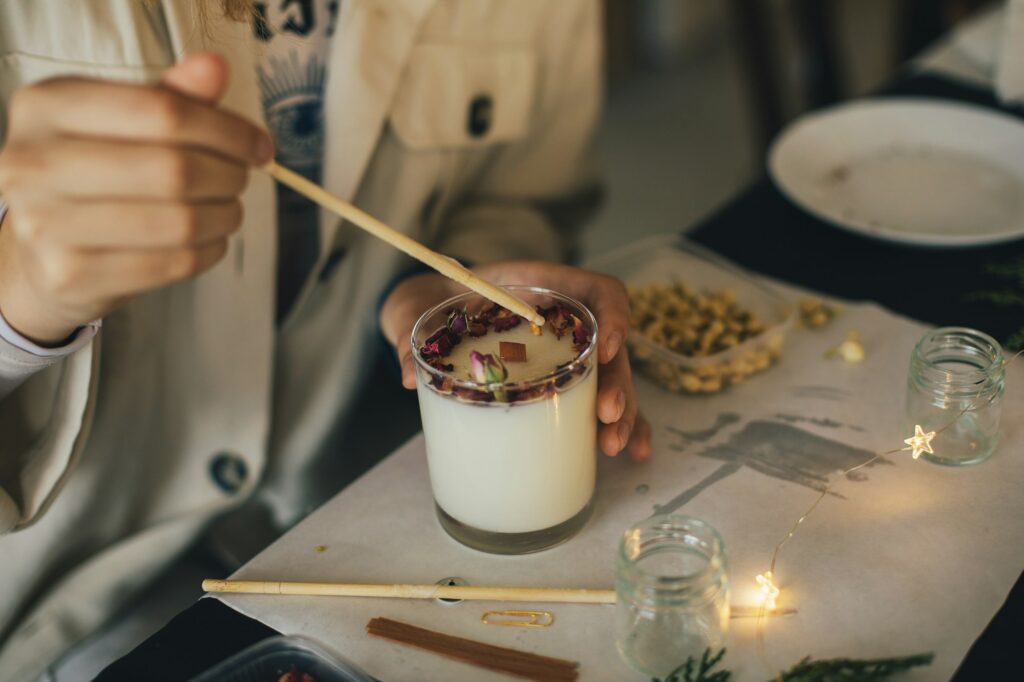 Millennial woman making candle using soy wax in workshop.