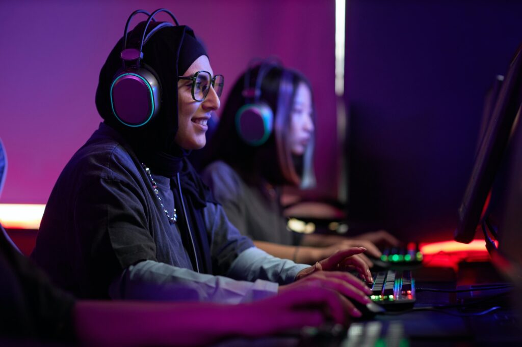 Muslim Woman Playing Video Games in Cybersports Club and Smiling Happily