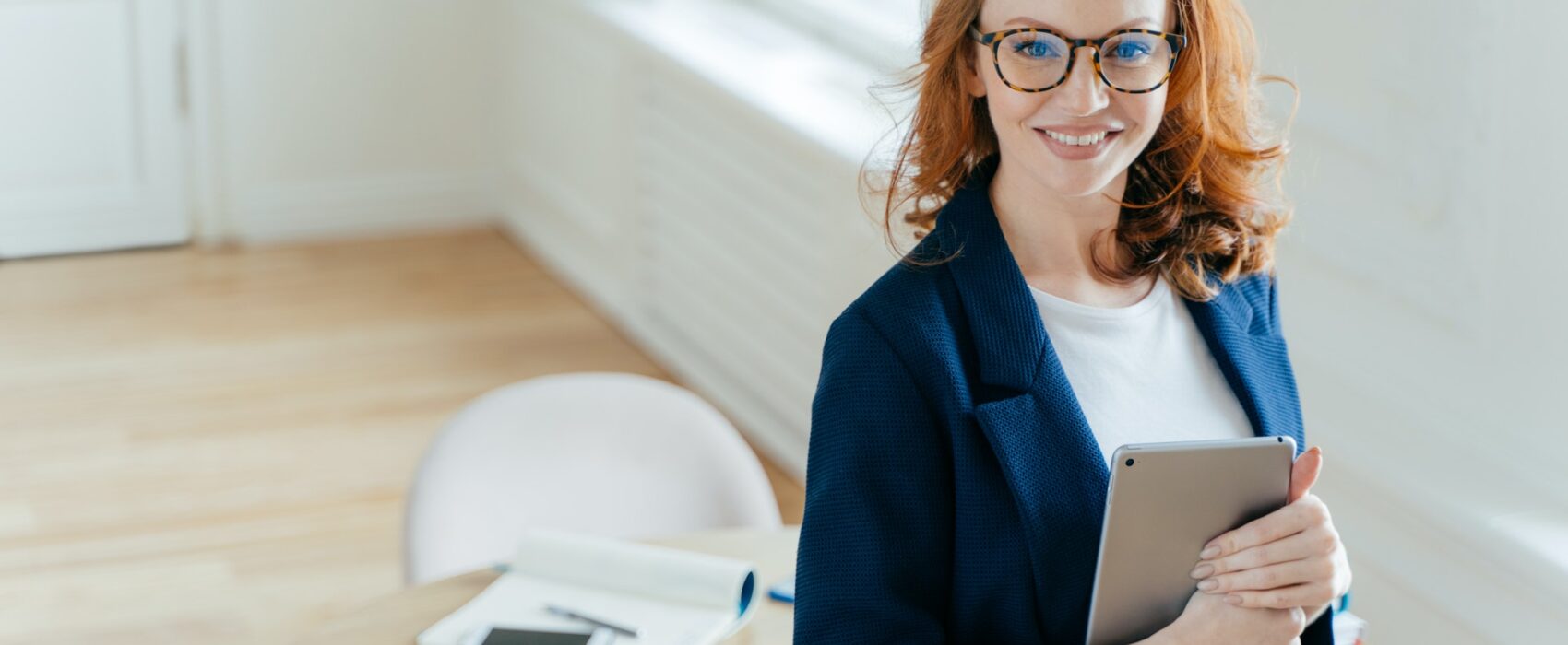 Prosperous female leader of working team holds digital tablet device, develops business ideas