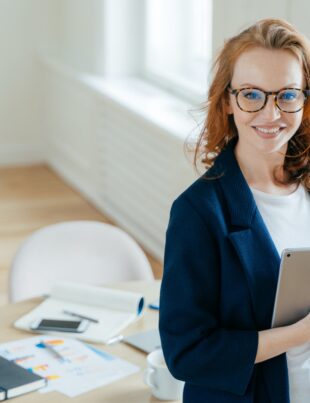 Prosperous female leader of working team holds digital tablet device, develops business ideas