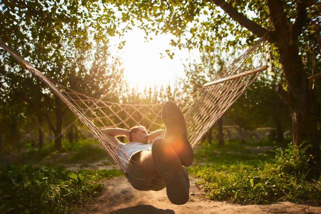 relaxing man in hammock rest in garden. summer vibes in park. digital detox in vacation on trip