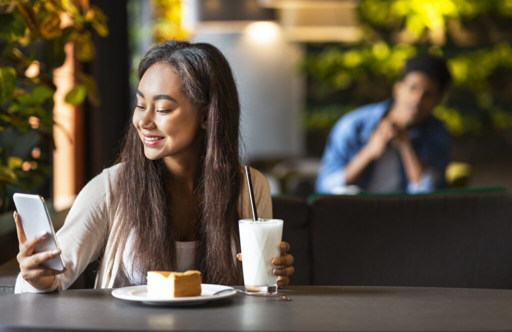 Young pretty girl using dating app in cafe