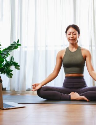 Asian woman yoga teacher filming yoga online class