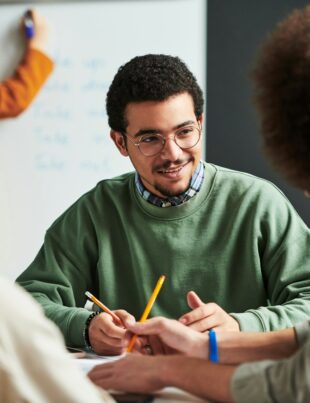 Happy young man in eyeglasses communicating with another student