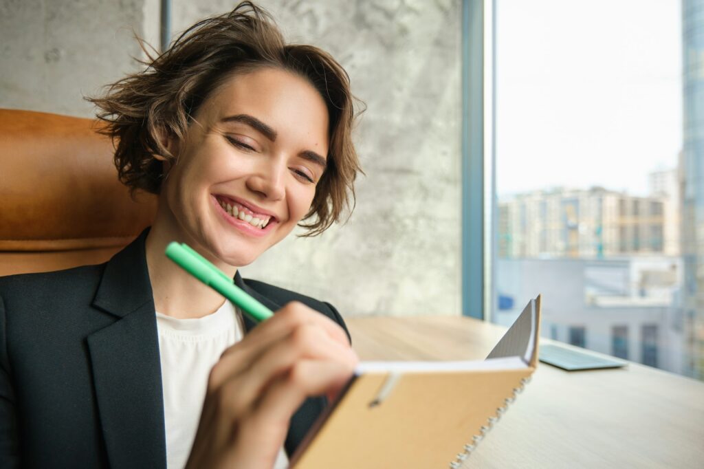 Successful businesswoman making notes, writing in her notebook, preparing for meeting in an office