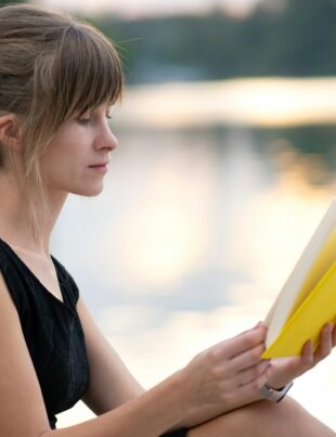 Young woman resting in summer park reading a book. Education and sudy concept